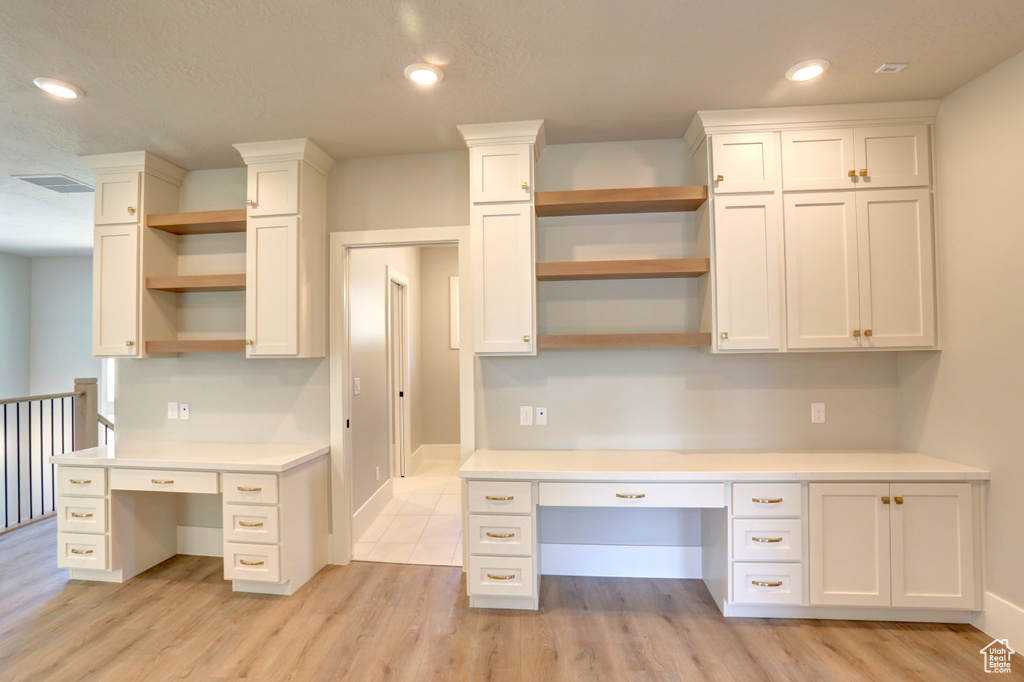 Unfurnished office with built in desk, light wood-type flooring, and recessed lighting