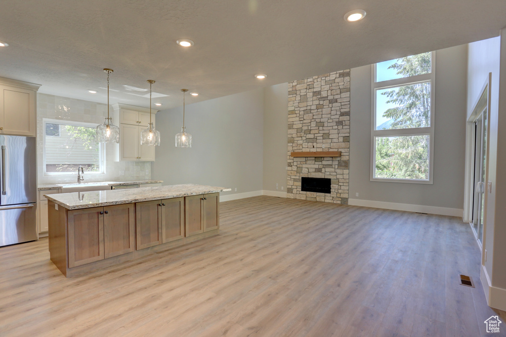 Kitchen featuring stainless steel refrigerator, a kitchen island, light wood-style flooring, tasteful backsplash, and recessed lighting