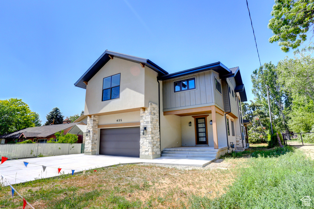 View of front facade featuring a garage, stone siding, concrete driveway, stucco siding, and board and batten siding