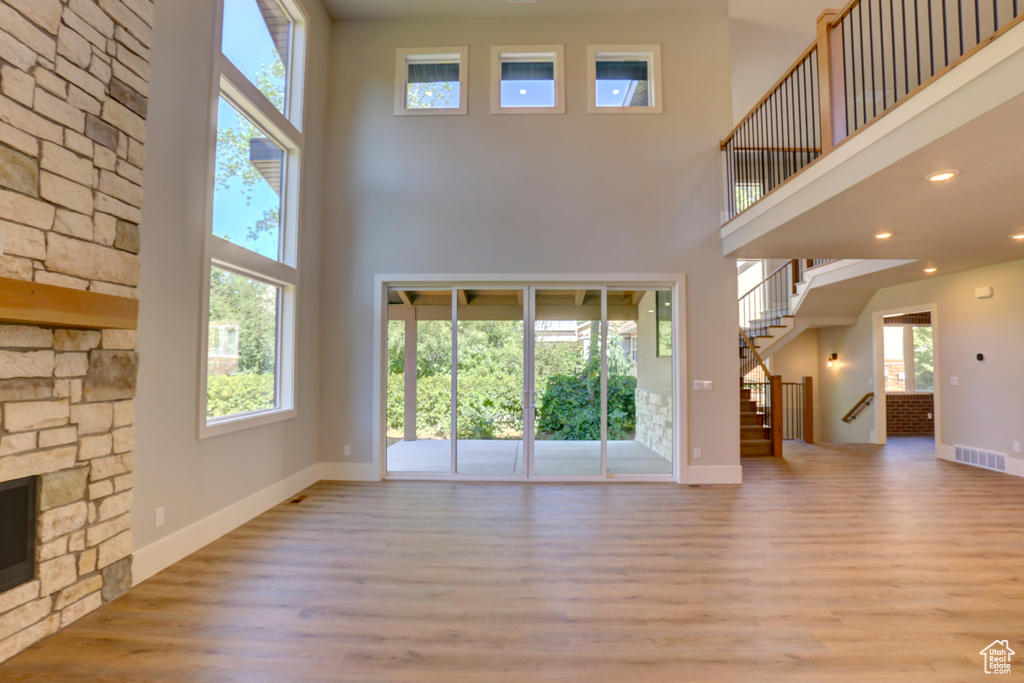Unfurnished living room with a high ceiling, wood finished floors, stairway, and recessed lighting