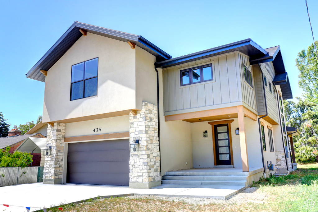 Contemporary house featuring a garage, stone siding, and stucco siding