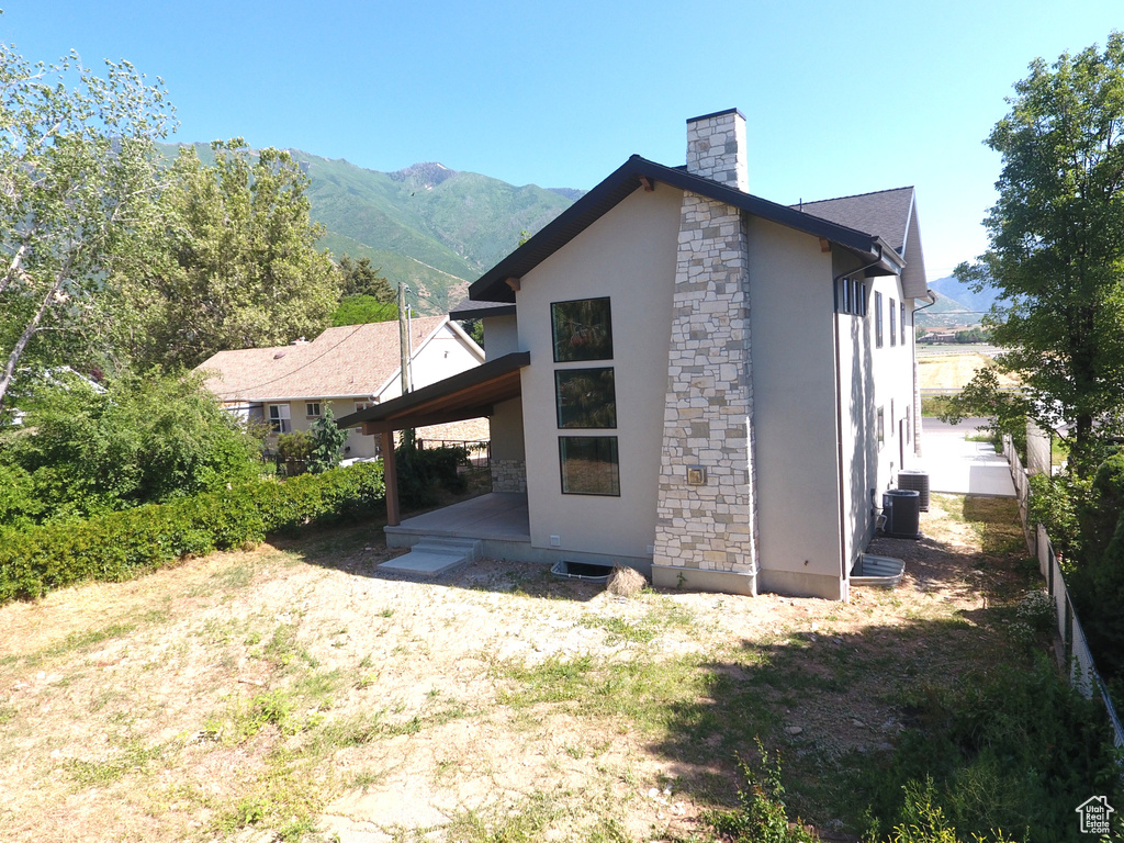 Back of property featuring stucco siding, stone siding, a chimney, and a mountain view