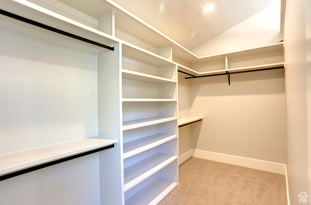 Walk in closet featuring light colored carpet and lofted ceiling