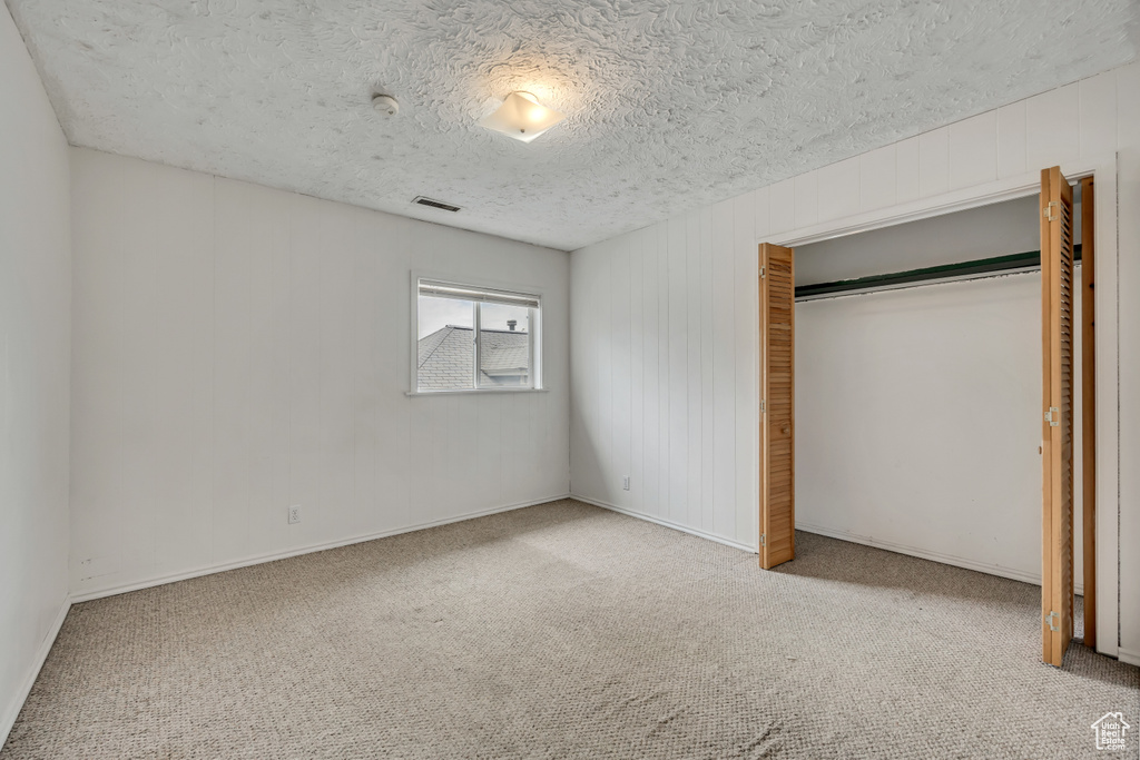Unfurnished bedroom with carpet, a textured ceiling, and a closet