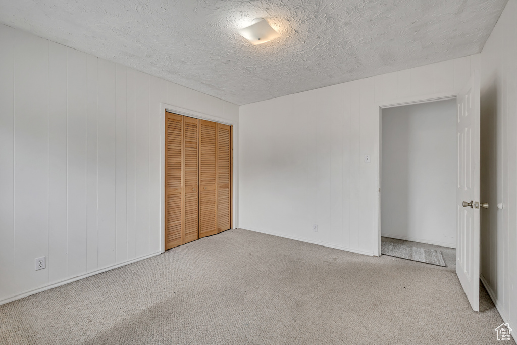 Unfurnished bedroom with carpet, a closet, and a textured ceiling