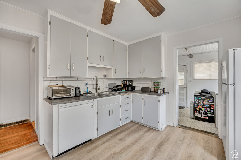 Kitchen with white appliances, a ceiling fan, decorative backsplash, and light wood-type flooring