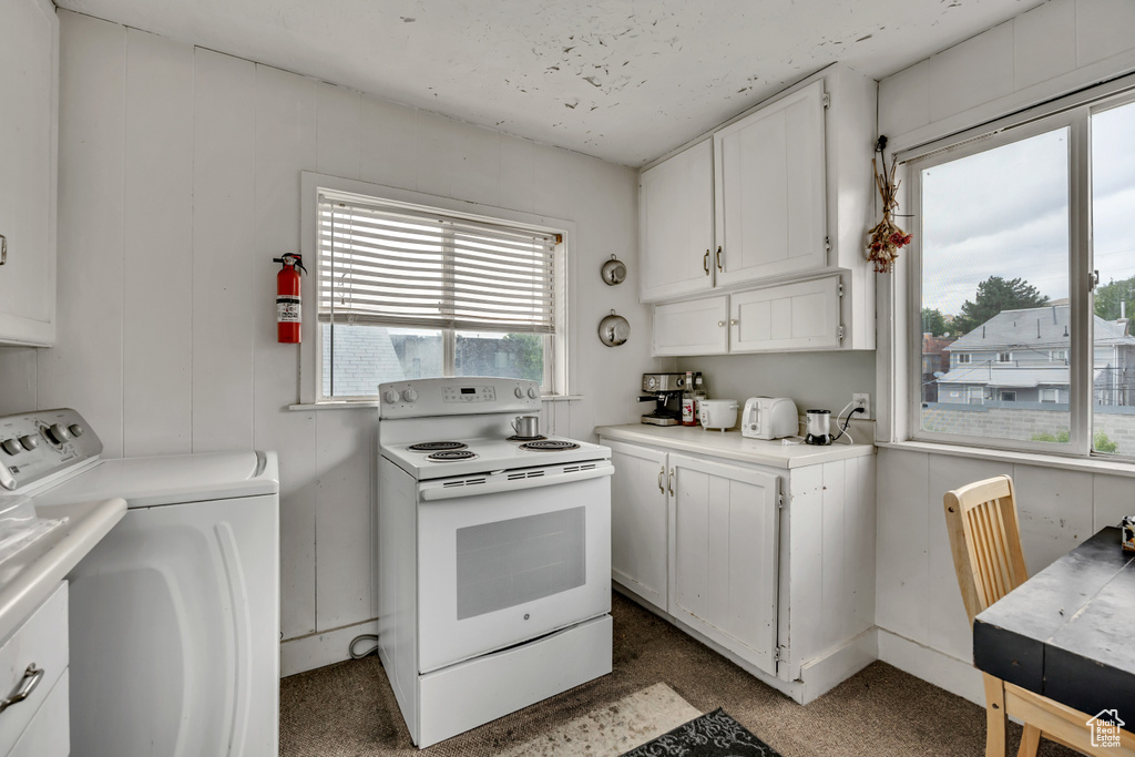 Kitchen featuring electric range, washing machine and dryer, white cabinetry, and light countertops