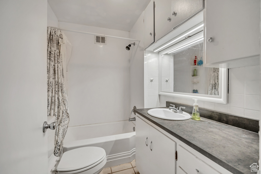 Bathroom featuring vanity, shower / tub combo with curtain, tile patterned flooring, and tasteful backsplash