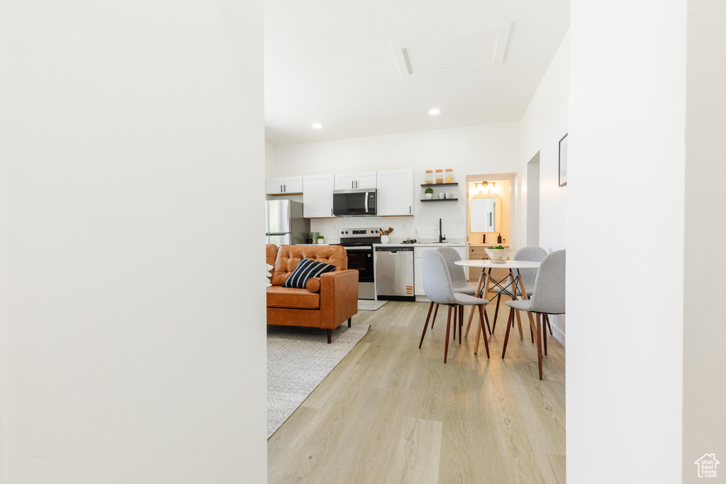 Living room featuring light wood finished floors, recessed lighting, and attic access