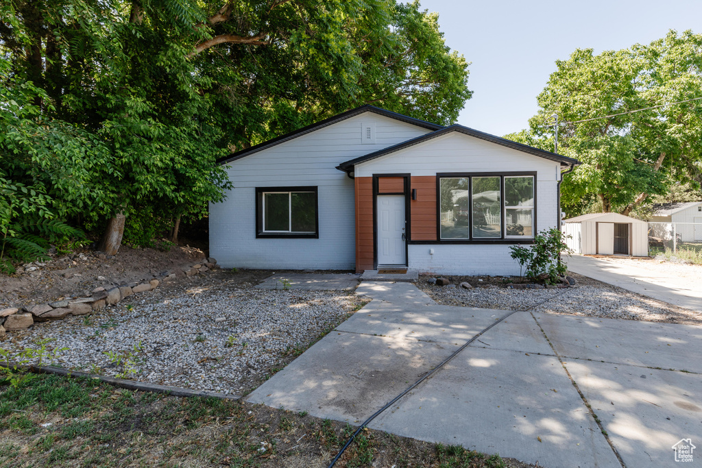 View of front facade featuring a storage shed, brick siding, and a patio area