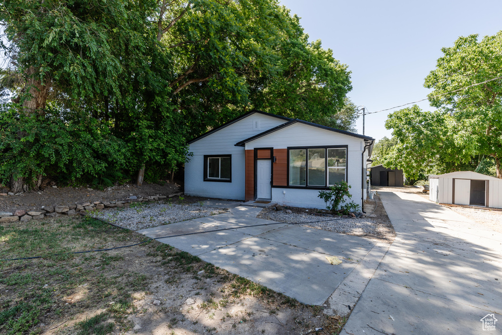 View of front of property with a storage shed and driveway