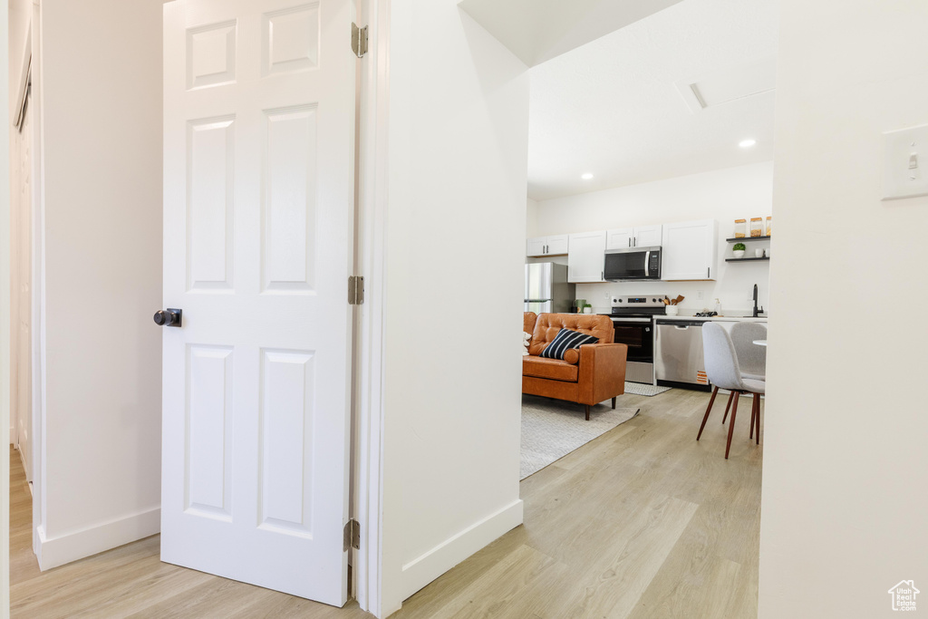Hallway with light wood finished floors and recessed lighting