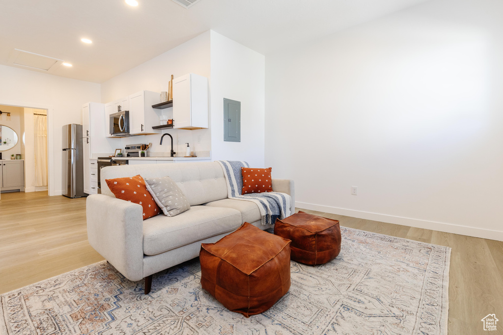 Living area featuring electric panel, light wood-type flooring, attic access, and recessed lighting