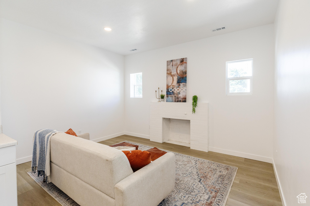 Living room with light wood-type flooring, a fireplace, and recessed lighting
