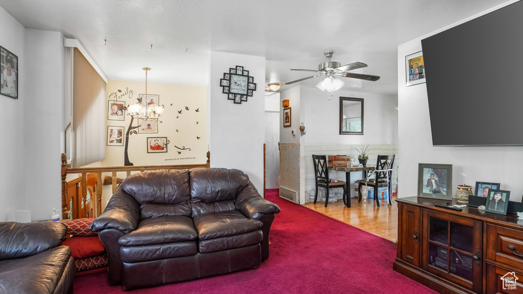 Living room featuring a chandelier, a ceiling fan, and carpet floors