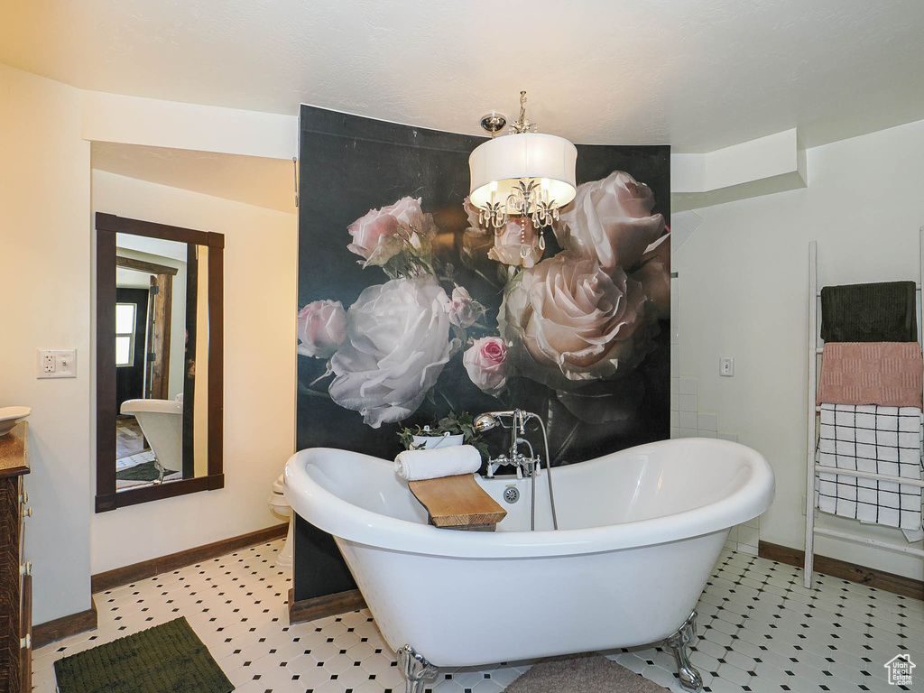 Bathroom with a freestanding tub, a chandelier, and vanity