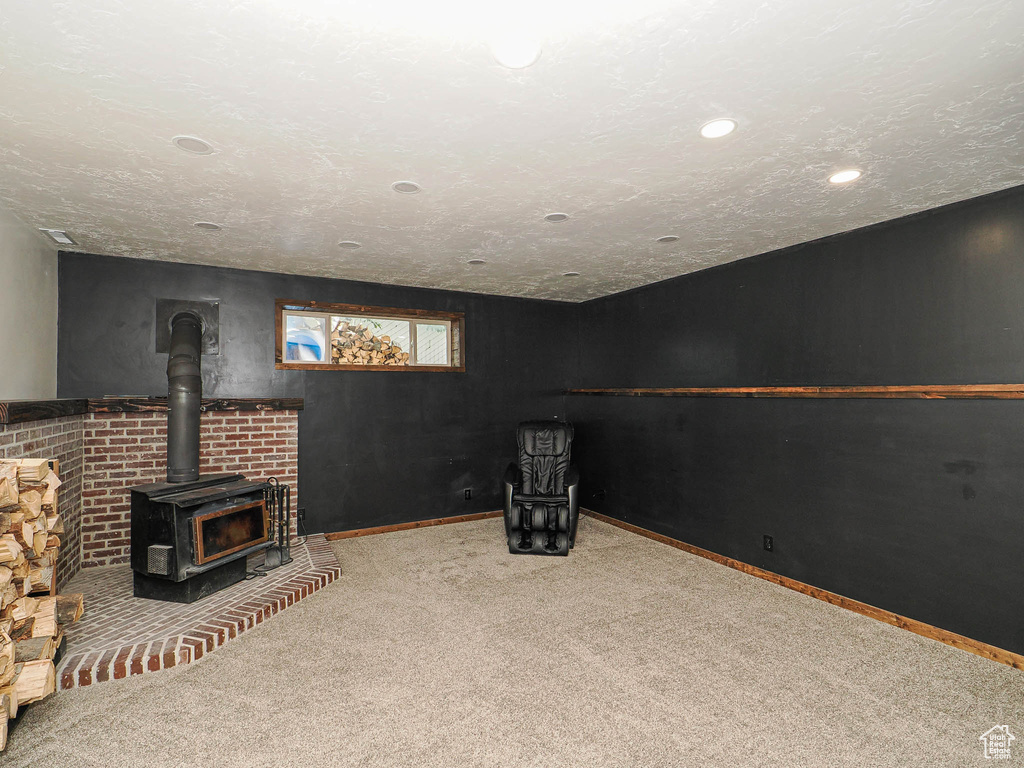 Below grade area with carpet flooring, a wood stove, and recessed lighting
