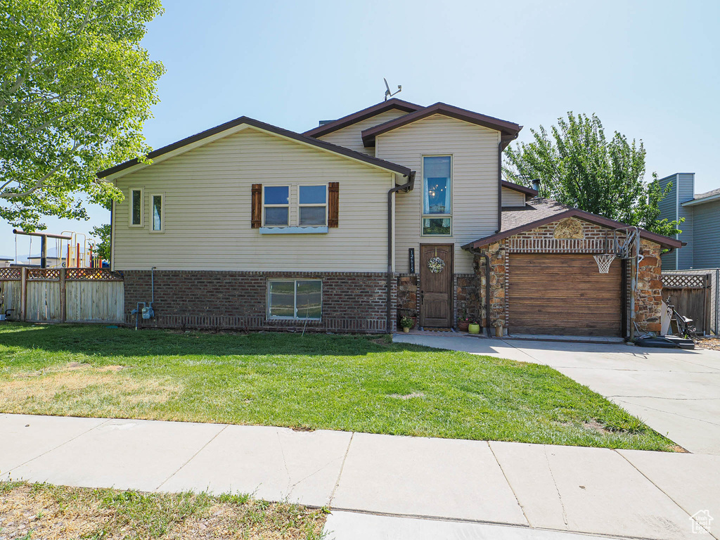 Split level home featuring concrete driveway, brick siding, and a garage