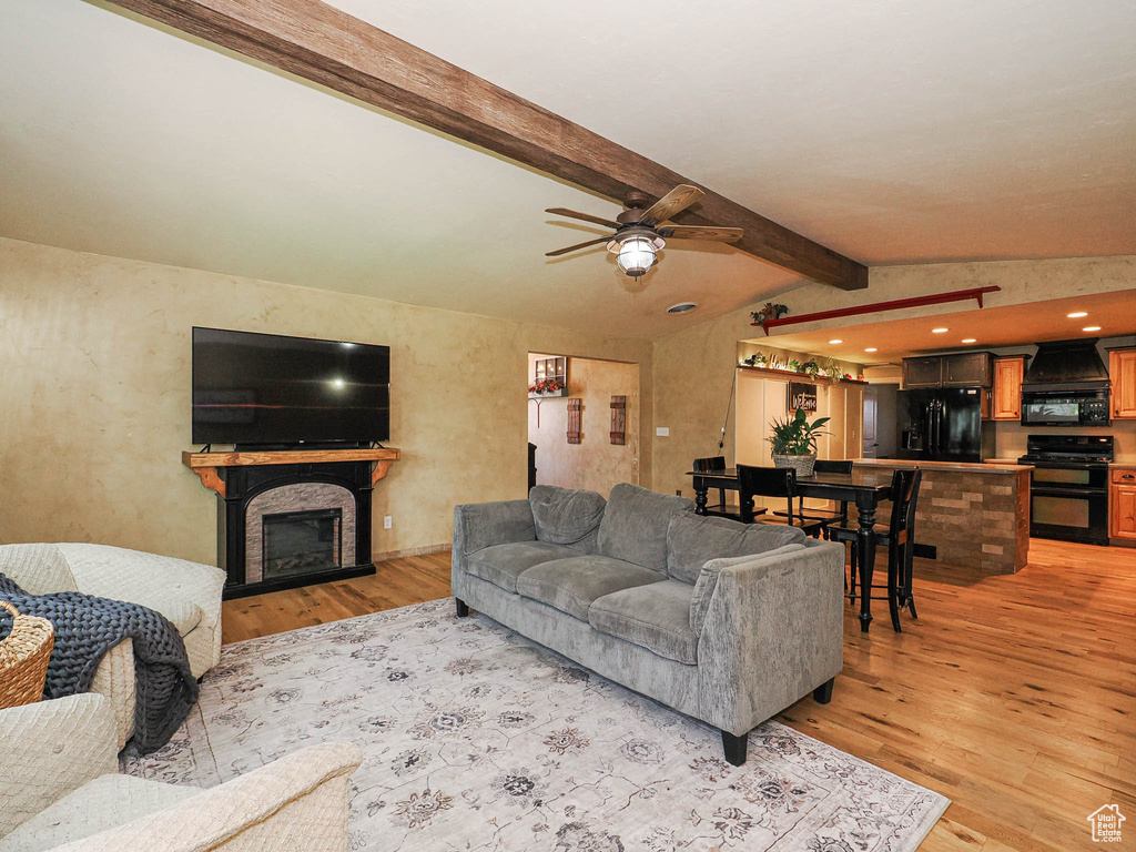 Living room featuring light wood-type flooring, a ceiling fan, and a fireplace