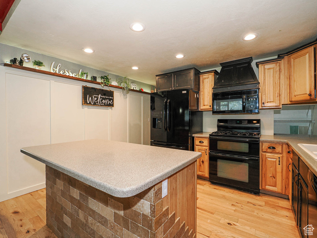 Kitchen featuring black appliances, light wood-style floors, a center island, light countertops, and recessed lighting