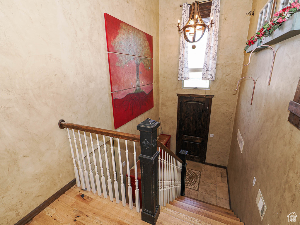 Staircase featuring wood finished floors and a chandelier
