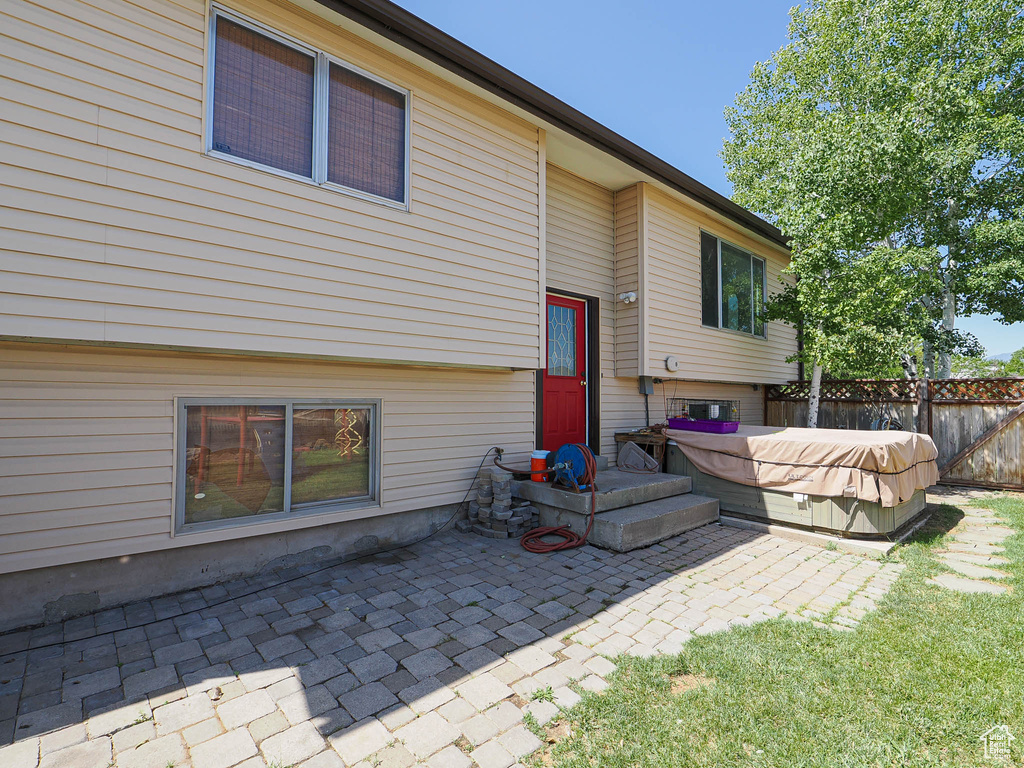 Rear view of property featuring a hot tub and a patio