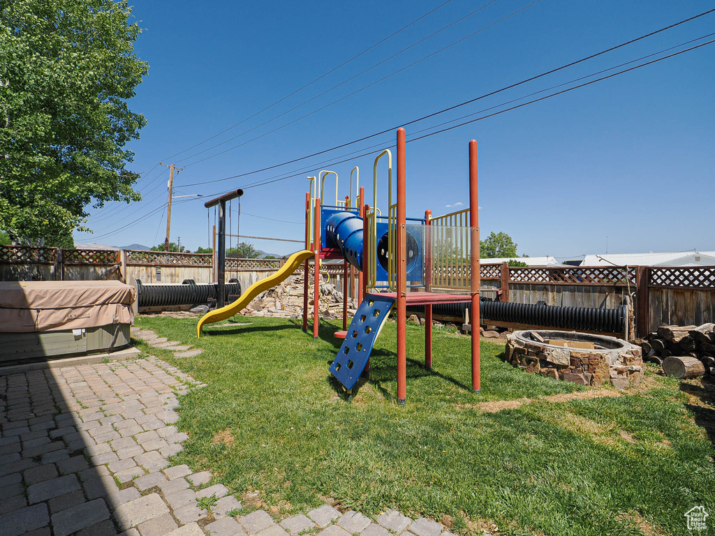 View of play area with a fenced backyard and a hot tub
