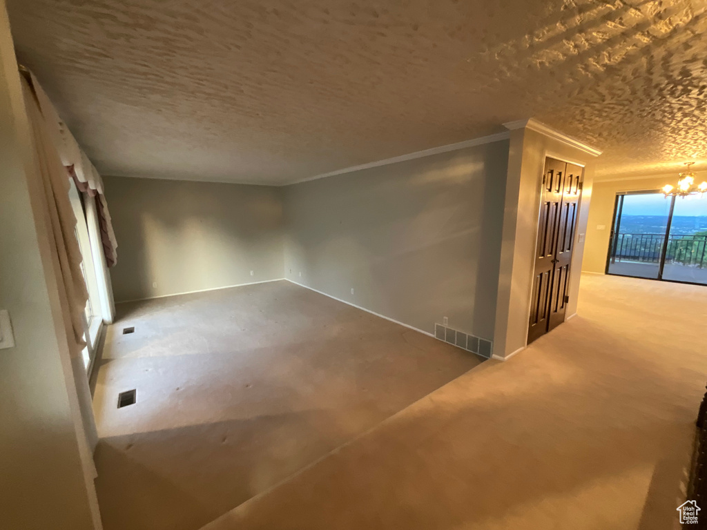 Unfurnished room featuring a chandelier, a textured ceiling, and crown molding