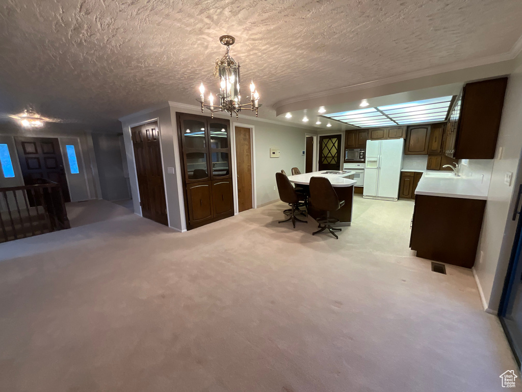 Dining area with a chandelier, a textured ceiling, light colored carpet, and ornamental molding