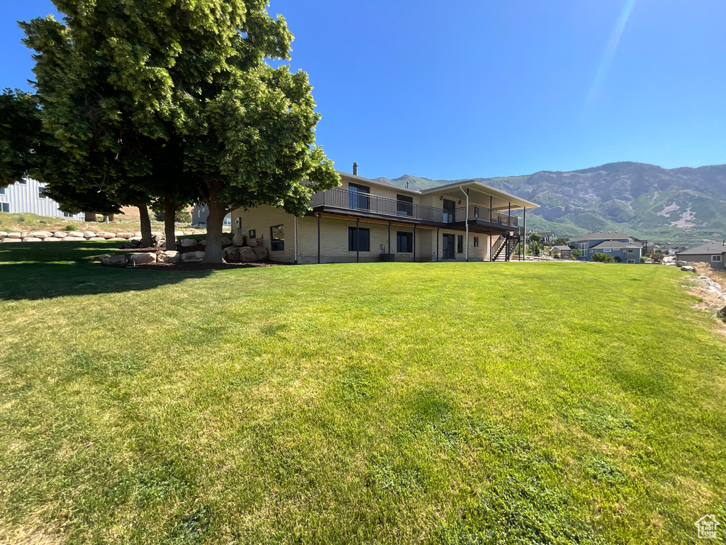 Back of property featuring a lawn, a deck with mountain view, and stairs
