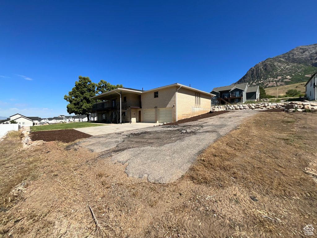 Rear view of house featuring a mountain view, asphalt driveway, and a garage