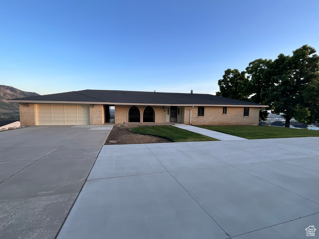 Ranch-style home with driveway, brick siding, a front lawn, and a garage