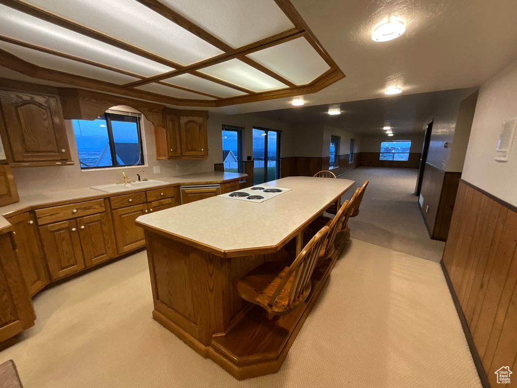 Kitchen featuring light carpet, a center island, a wainscoted wall, light countertops, and a breakfast bar area