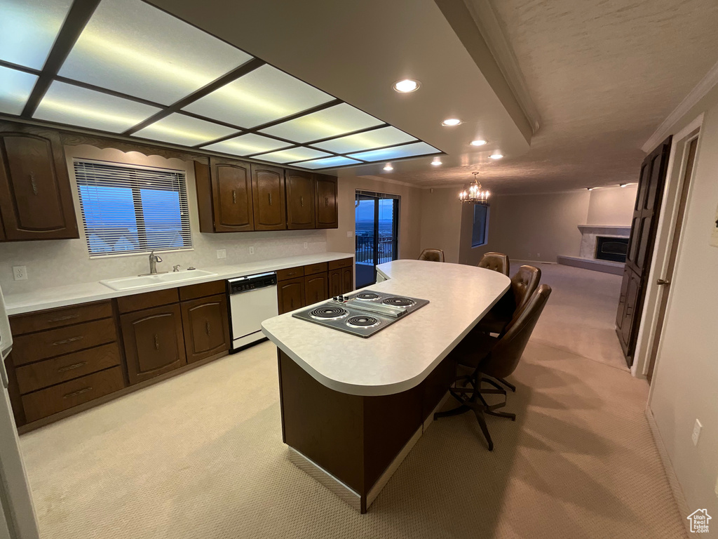 Kitchen with white dishwasher, electric stovetop, light colored carpet, dark brown cabinets, and recessed lighting