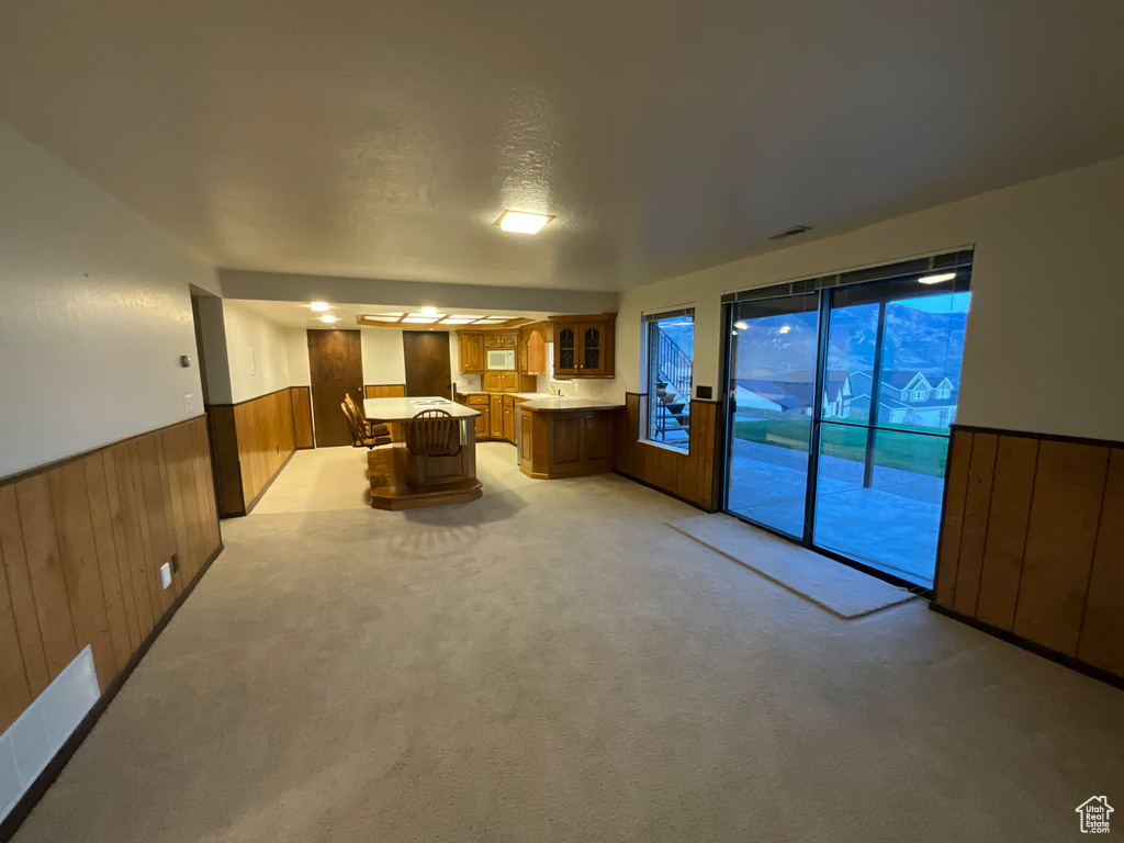 Kitchen featuring brown cabinets, wainscoting, light countertops, glass insert cabinets, and wood walls