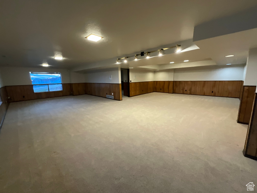 Basement featuring a wainscoted wall, wooden walls, and light carpet