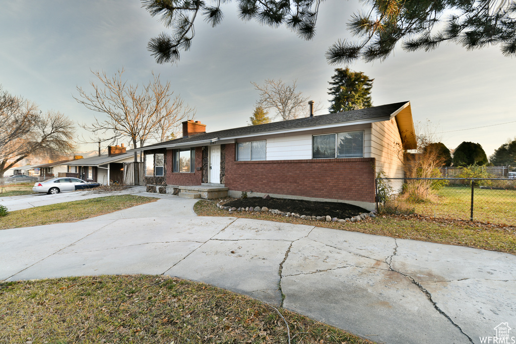 Ranch-style home with brick siding, a chimney, and concrete driveway