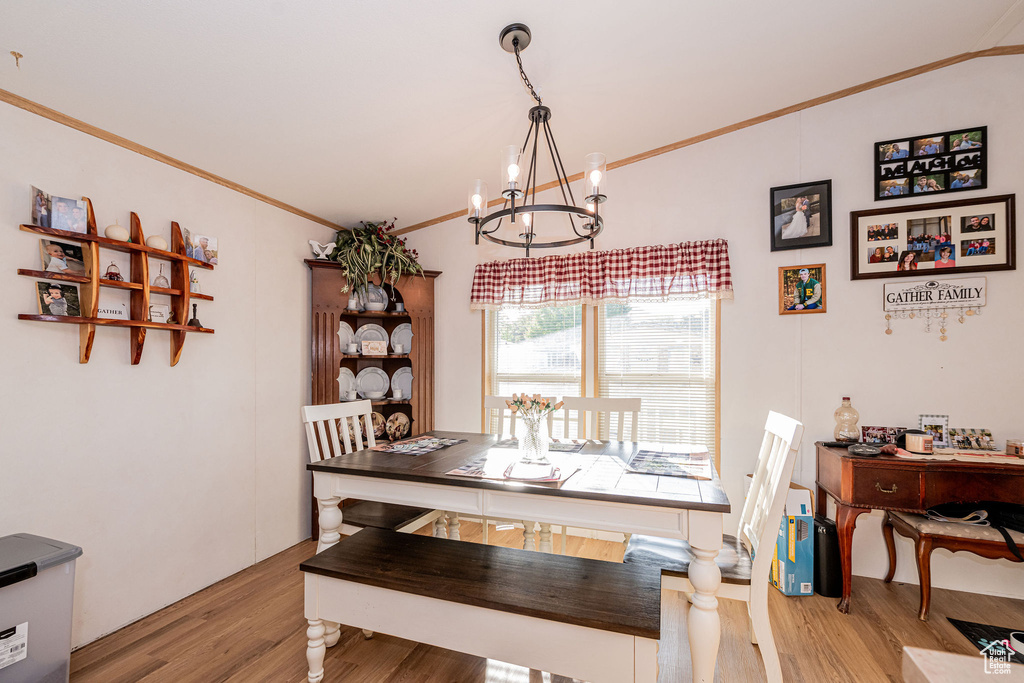 Dining area with a chandelier, wood finished floors, and crown molding