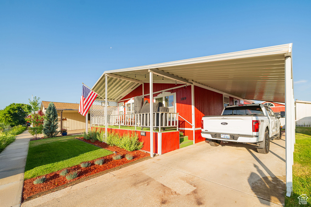 Manufactured / mobile home featuring a front lawn, a carport, covered porch, and driveway