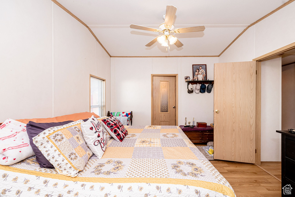 Bedroom featuring ornamental molding, light wood finished floors, lofted ceiling, and a ceiling fan
