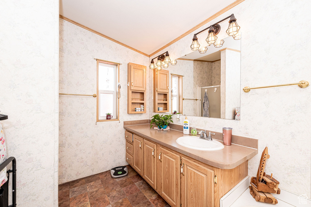 Bathroom featuring ornamental molding, wallpapered walls, vanity, a chandelier, and lofted ceiling