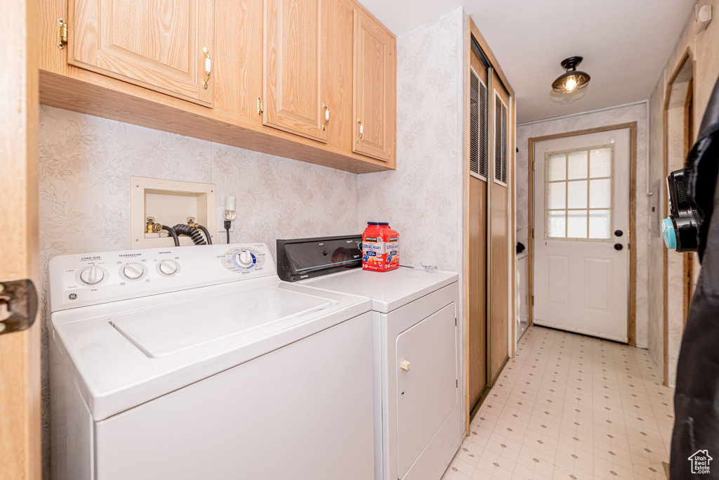 Laundry area featuring cabinet space, washer and clothes dryer, light flooring, and wallpapered walls