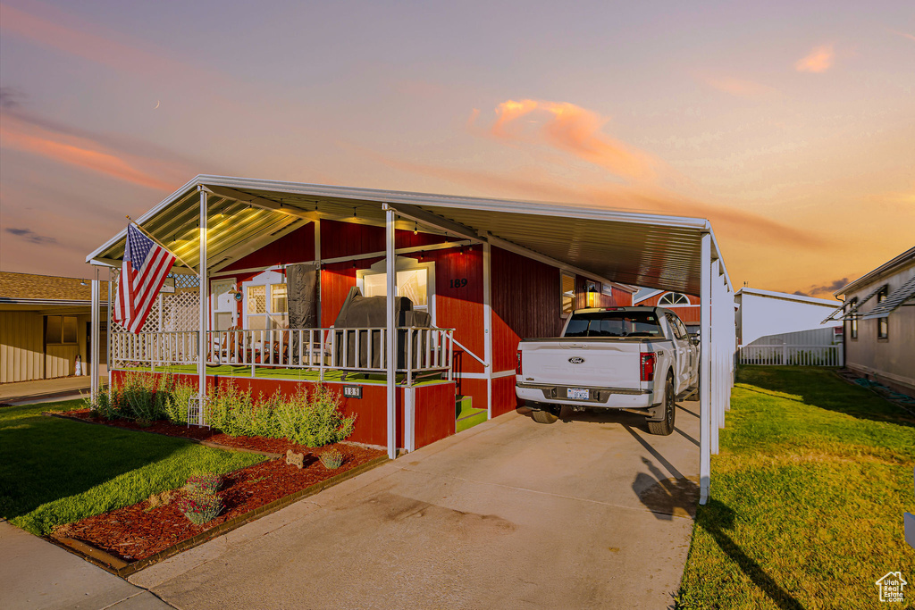 Manufactured / mobile home with a front yard, a carport, driveway, and covered porch