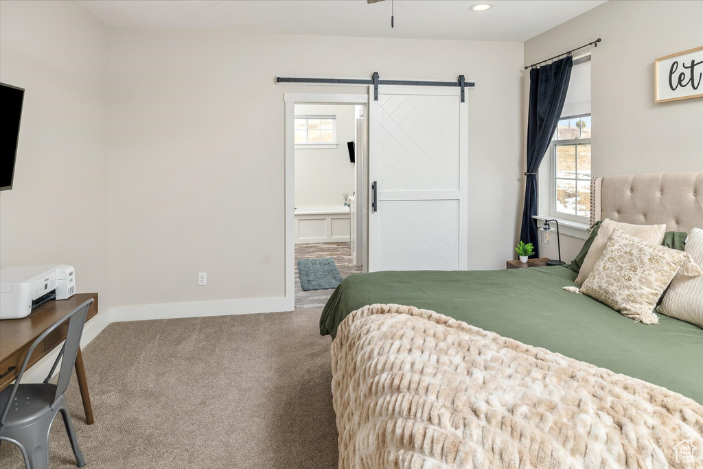 Carpeted bedroom with a barn door, connected bathroom, and recessed lighting