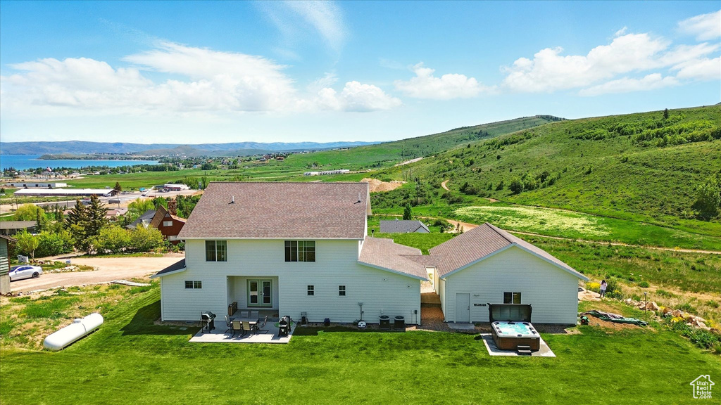 Rear view of house with a water and mountain view, a patio area, and a yard