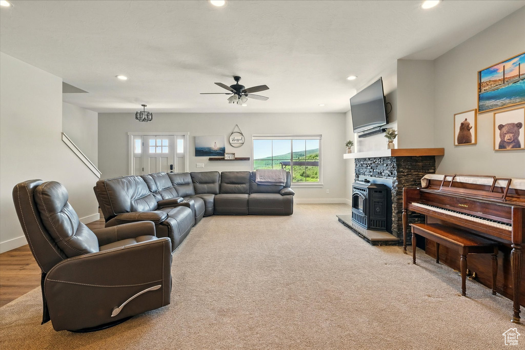 Living area with recessed lighting, a ceiling fan, light carpet, and a wood stove
