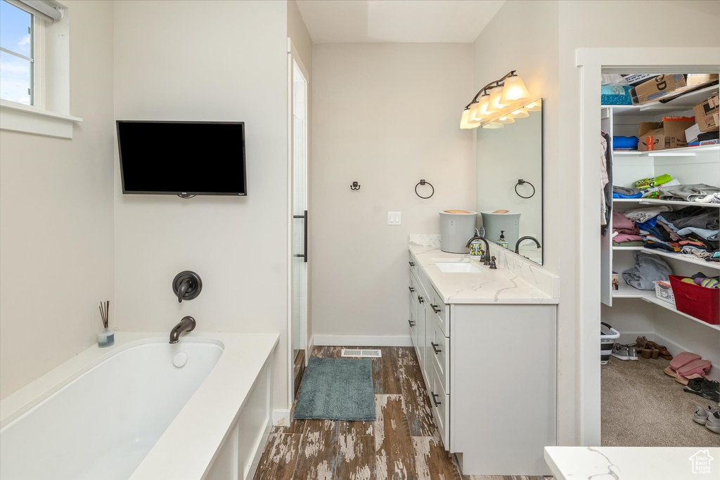 Bathroom featuring vanity, a bath, and wood finished floors