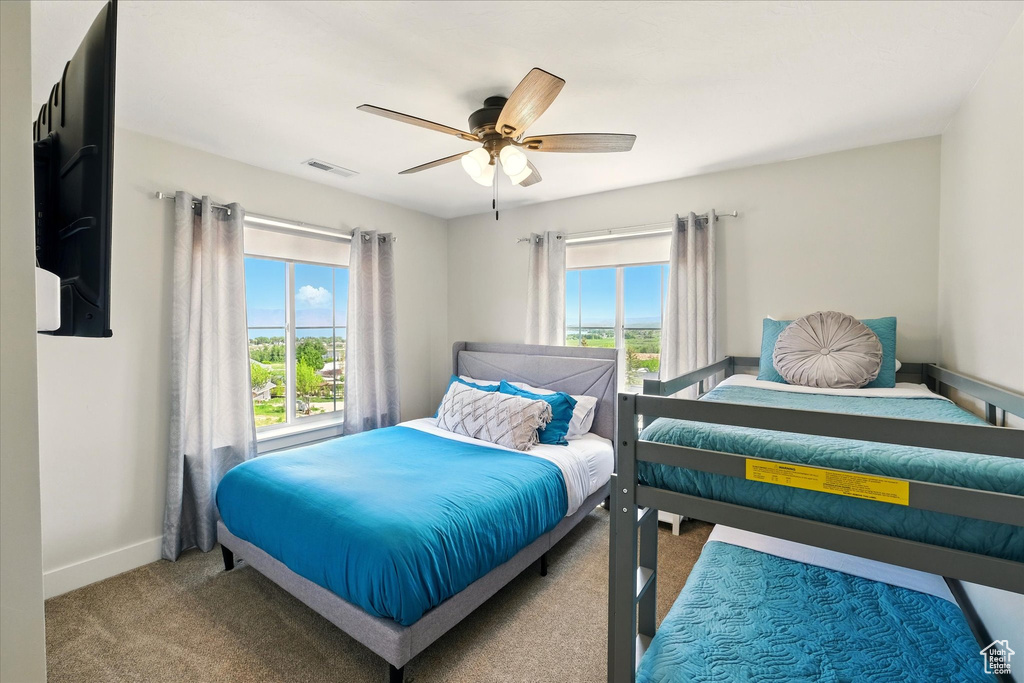 Bedroom with multiple windows, carpet floors, and a ceiling fan