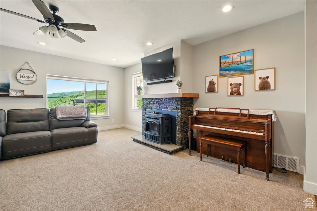 Carpeted living area with a wood stove, recessed lighting, and a ceiling fan