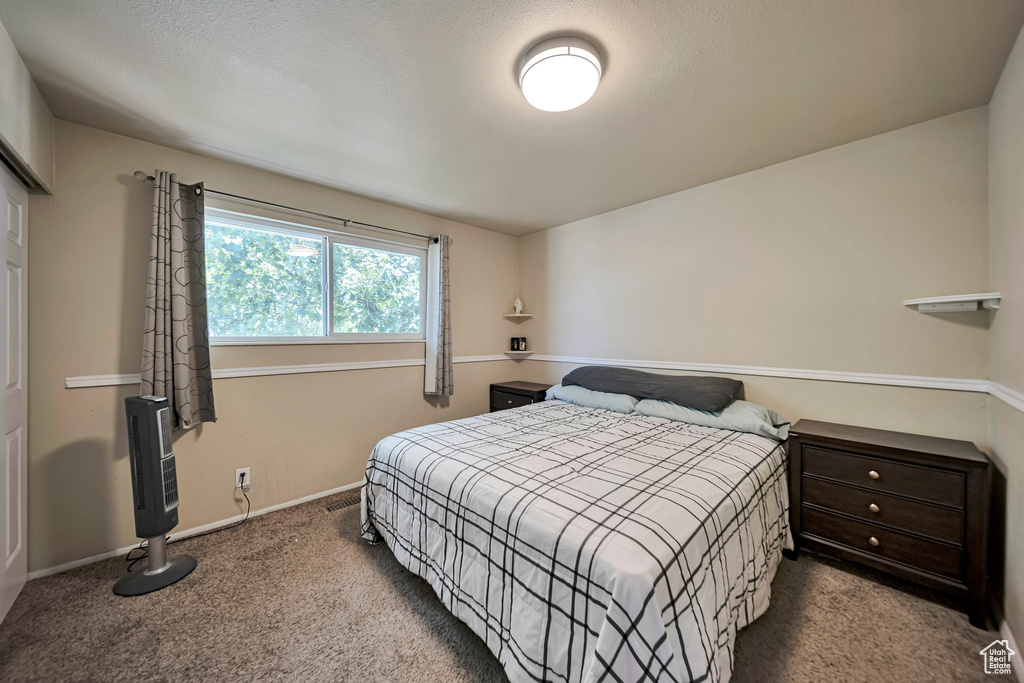 Carpeted bedroom with baseboards and heating unit